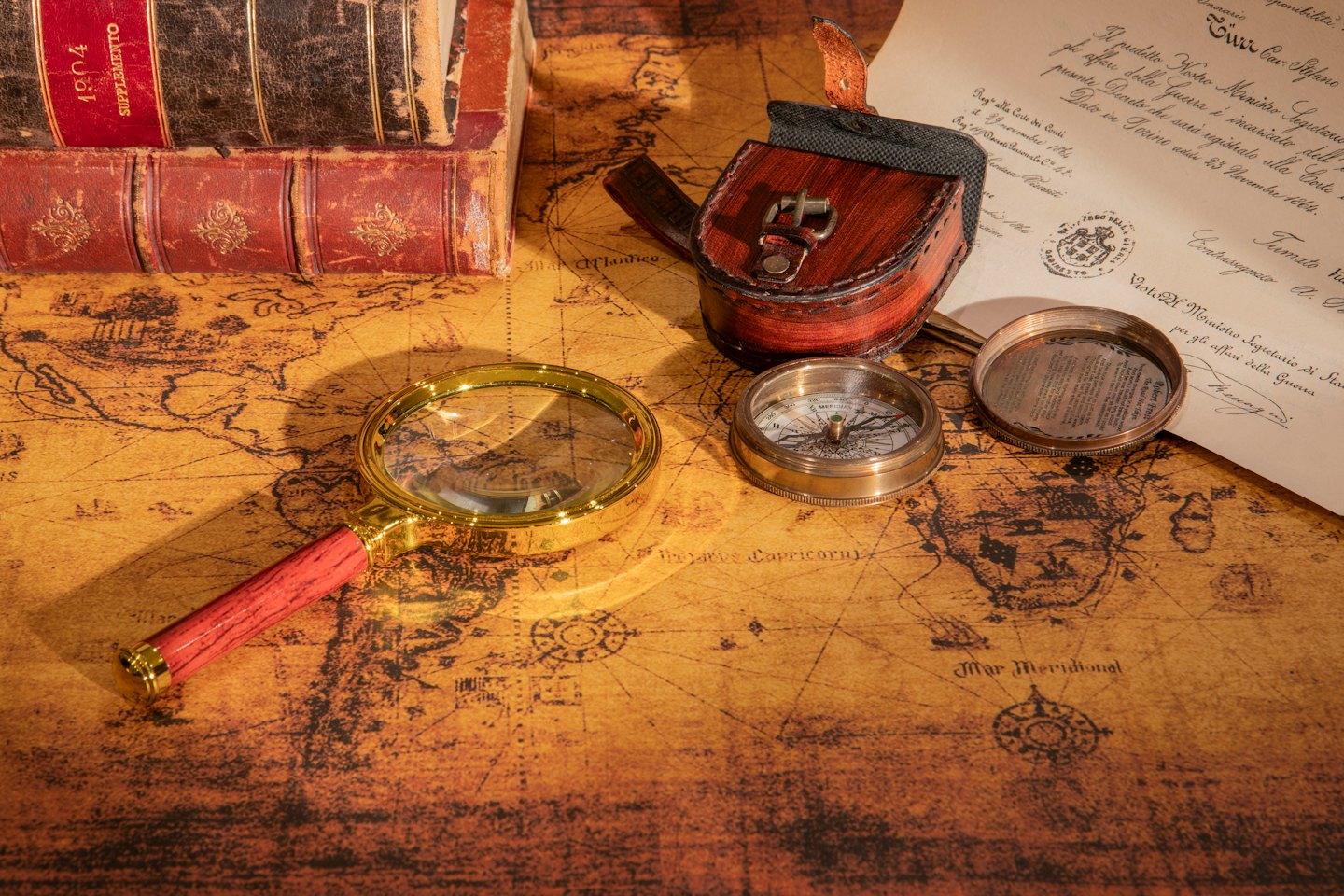 Mappa antica con lente d'ingrandimento, bussola e vecchi libri.