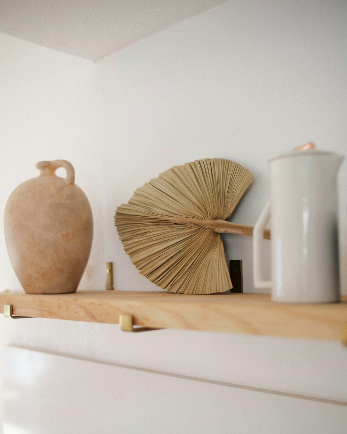 Caraffa e brocca in ceramica decorativa con foglia di palma su mensola.