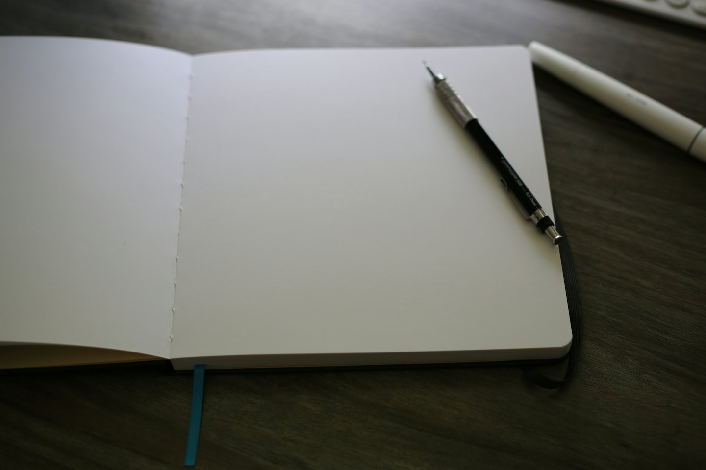 Un quaderno aperto con una matita su una scrivania di legno.
