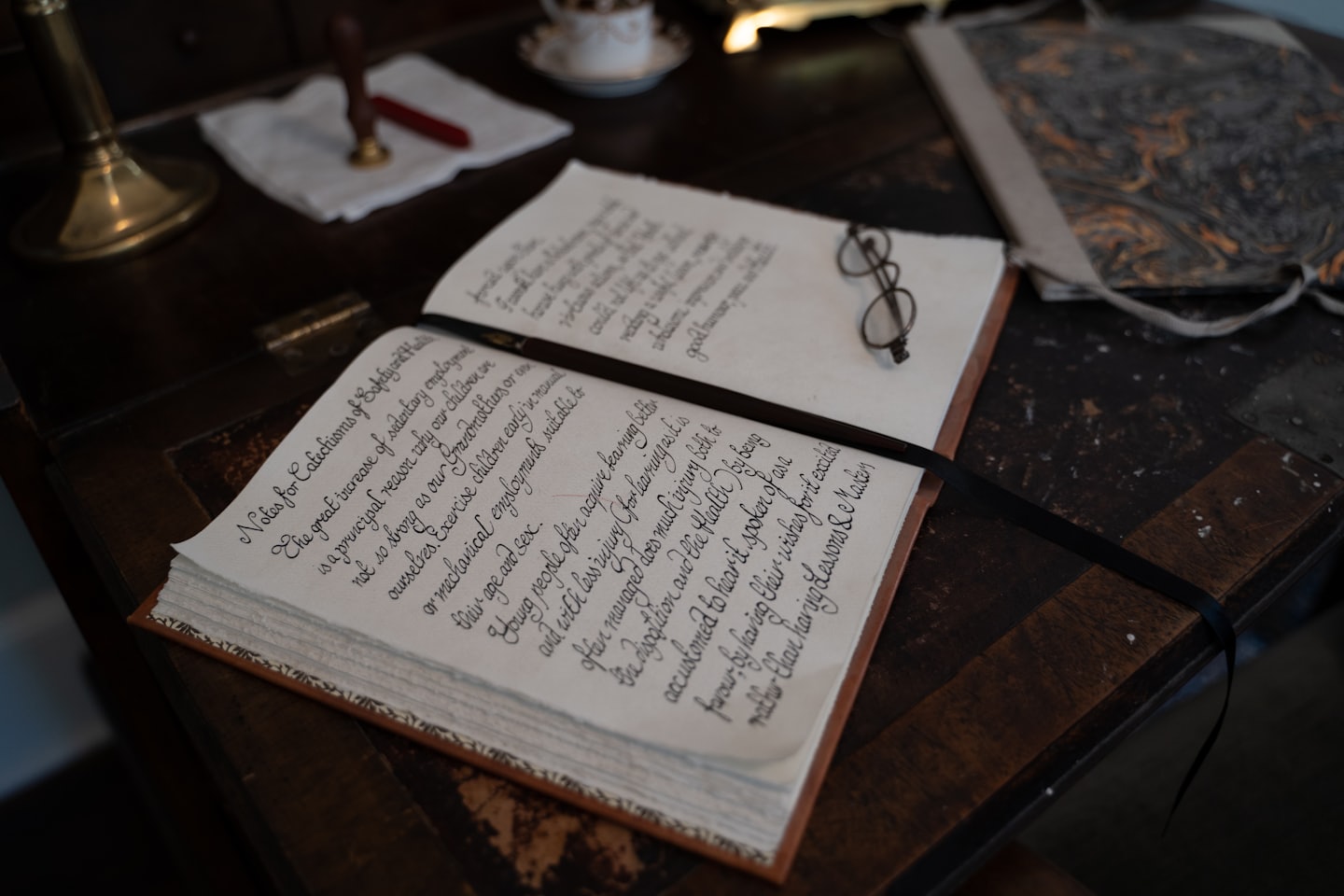 Occhiali da vista appoggiati su un diario aperto scritto a mano su una scrivania.